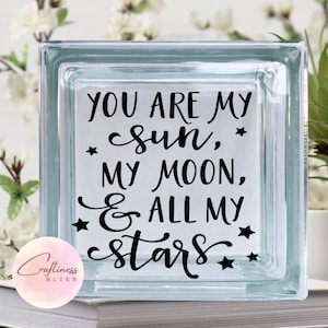 May include: A clear glass block with the text "You are my sun, my moon, & all my stars" in black lettering with small stars around the text.