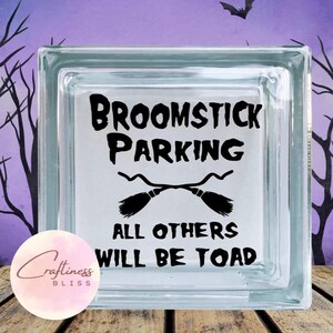 May include: A glass block with a black vinyl decal that reads "Broomstick Parking" with a graphic of two crossed broomsticks and the text "All others will be toad".