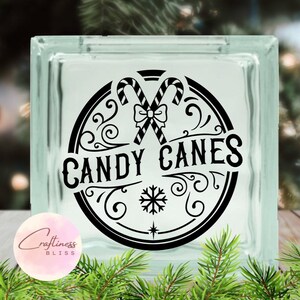 May include: Black and white graphic design of two candy canes with a bow and a snowflake in a circle with the text "Candy Canes".