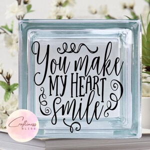 May include: A clear glass block with the text "You make my heart smile" in black lettering.