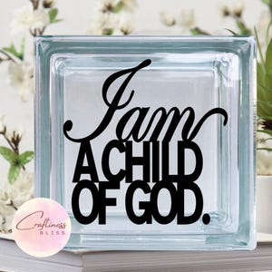 May include: A glass block with the words "I am a child of God." in black lettering.