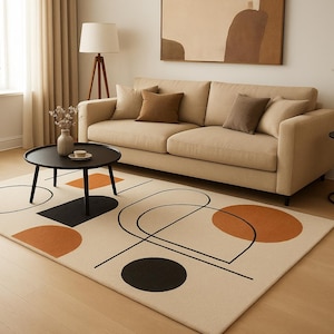 Può includere: Un soggiorno moderno con un divano beige, cuscini marroni e un tavolino nero. Il tappeto presenta uno sfondo crema con forme geometriche nere e arancioni. La stanza ha una palette di colori neutri e pavimenti in legno.