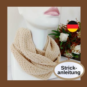 May include: A cream-colored knitted infinity scarf displayed on a mannequin. The scarf is looped around the mannequin's neck, showcasing its texture and design. The image includes a German flag and the text "Strickanleitung".