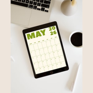 May include: A black tablet showing a May 2026 calendar, with green text. The tablet is on a white surface, with a laptop, a coffee cup, a pen, and a decorative vase. The calendar is a useful tool for planning.