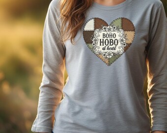 Könnte beinhalten: Hellgraues Langarmshirt mit herzförmigem Design. Das Herz ist ein Patchwork aus braunen, grünen und cremefarbenen Stoffen, mit floralen Akzenten und dem Text "BOHO HOBO at heart" in einem dekorativen Rahmen.