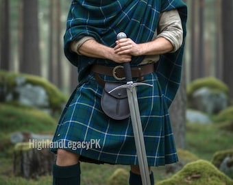 Può includere: Una persona indossa un kilt a quadri blu e verdi con uno scialle in tartan abbinato sopra una camicia beige a maniche lunghe. L'abbigliamento include una cintura in pelle marrone con sporran, calzettoni neri al ginocchio e stivali neri.