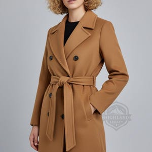 May include: A camel-colored double-breasted coat with a matching belt tied at the waist. The coat features a classic lapel collar, pockets, and black buttons. The coat is knee-length and made of a smooth fabric.