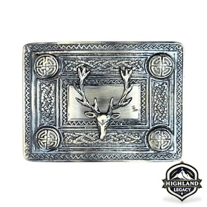 May include: A rectangular silver-toned belt buckle with a stag head design. The buckle features Celtic knotwork and circular accents. The Highland Legacy logo is in the bottom right corner.