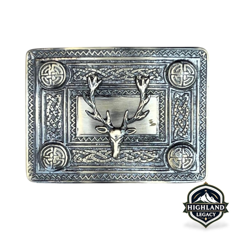 May include: A rectangular silver-toned belt buckle with a stag head design. The buckle features Celtic knotwork and circular accents. The Highland Legacy logo is in the bottom right corner.