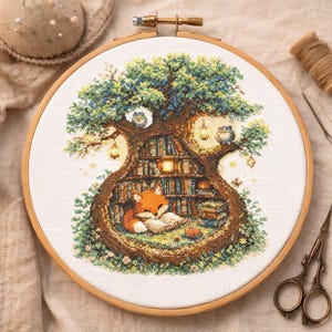 May include: A cross-stitch embroidery in a wooden hoop depicts a whimsical scene. A fox reads in a tree-shaped library, surrounded by books, owls, and lanterns. The artwork features a detailed design with various colors, creating a cozy, storybook atmosphere.