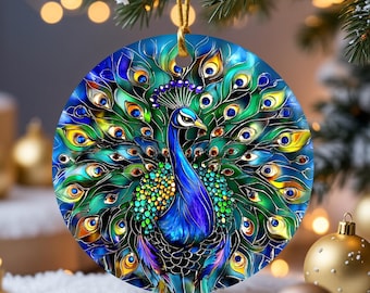 Könnte beinhalten: Runder Weihnachtsschmuck mit einem Pfauenmotiv. Der Pfau ist mit leuchtenden blauen, grünen und gelben Federn dargestellt, die an Buntglas erinnern. Der Schmuck wird an einer goldenen Schnur aufgehängt, vor einem schneebedeckten Untergrund und Weihnachtsdekorationen.