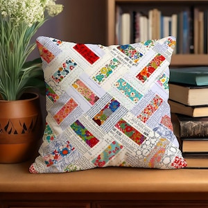 Könnte beinhalten: Quadratisches Zierkissen mit Patchwork-Design. Das Kissen hat einen weißen Hintergrund mit einem sich wiederholenden Muster aus farbigen rechteckigen Flicken. Die Flicken sind mit Blumendrucken und Text gefüllt, was einen einzigartigen und strukturierten Look erzeugt.