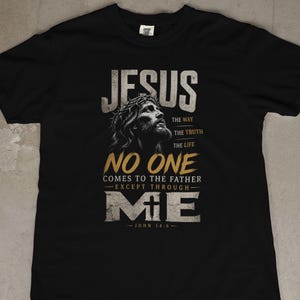 May include: A black short-sleeved t-shirt featuring a graphic of Jesus wearing a crown of thorns. The text reads: JESUS THE WAY THE TRUTH THE LIFE NO ONE COMES TO THE FATHER EXCEPT THROUGH ME JOHN 14:6. The design uses white and gold lettering.