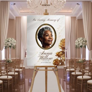 May include: A memorial sign with a portrait of a woman in a gold frame, with the text "In Loving Memory of Anna Willow." The sign is displayed on a wooden easel in a decorated hall with floral arrangements and seating.