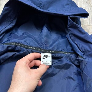 Może przedstawiać: Rustykalny drewniany szyld z napisem "Welcome to our home" w białych literach. Szyld ma postarzaną powierzchnię i prosty, zachęcający design, idealny do dekoracji wejścia.