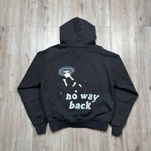 Może przedstawiać: Czarna bluza z kapturem z grafiką na plecach przedstawiającą UFO, postać i biały napis "no way back". Bluza posiada kaptur ze sznurkiem oraz prążkowane mankiety i d&oacute;ł.