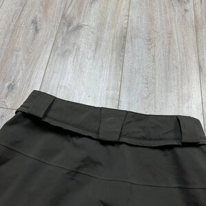 May include: A white ceramic mug with a black handle and the text "But First, Coffee" in a bold, black font. The mug is set against a blurred background, suggesting a cozy setting.