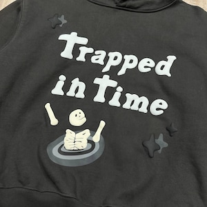 Może przedstawiać: Biały ceramiczny kubek z czarnym uchwytem i napisem "But First, Coffee" pogrubioną czcionką. Kubek stoi na drewnianej powierzchni. Kubek ma około 10 cm wysokości.