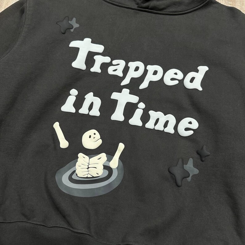 Może przedstawiać: Biały ceramiczny kubek z czarnym uchwytem i napisem "But First, Coffee" pogrubioną czcionką. Kubek stoi na drewnianej powierzchni. Kubek ma około 10 cm wysokości.