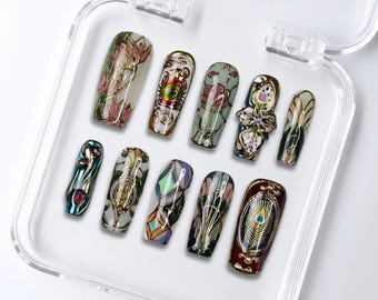 May include: A set of ten press-on nails in a clear plastic case. The nails feature intricate designs with floral, peacock feather, and abstract patterns in gold, red, green, and blue hues. The nails are in various shapes and sizes.