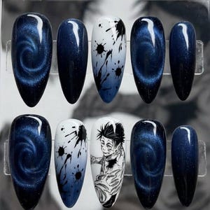 Pode incluir: Conjunto de dez unhas postiças ovais em uma caixa de plástico transparente. Os designs incluem redemoinhos de galáxia azul escuro, unhas brancas com respingos pretos e uma ilustração de personagem de anime em preto e branco.