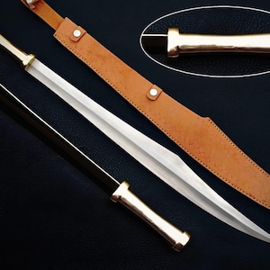May include: A silver and gold sword with a leather sheath. The sword has a long, double-edged blade and a gold handle. The sheath is brown and has a strap. The sword is approximately 76 cm long.