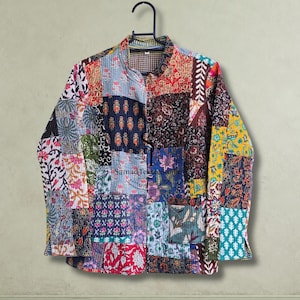 Puede incluir: Una chaqueta de manga larga con un diseño de patchwork de varios patrones florales y geométricos en colores como rojo, azul, amarillo y verde. La chaqueta tiene un cuello mao, cierre frontal de botones y un logotipo de texto visible.
