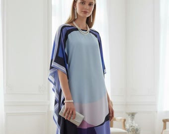 May include: A floor-length, geometric-patterned dress in shades of blue, purple, and black. The dress features a flowing silhouette with a cape-like sleeve design. The model is wearing white heels and holding a silver clutch.