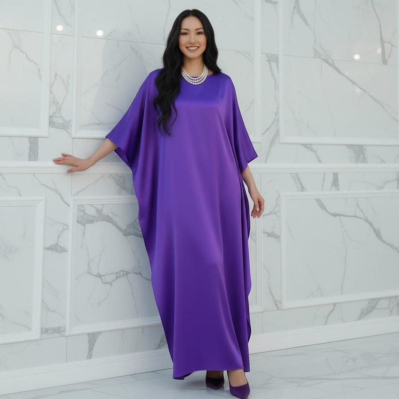 May include: A long, flowing, purple dress with wide sleeves. The dress is made of a smooth, shiny fabric and is worn with matching purple shoes. A pearl necklace is also worn.