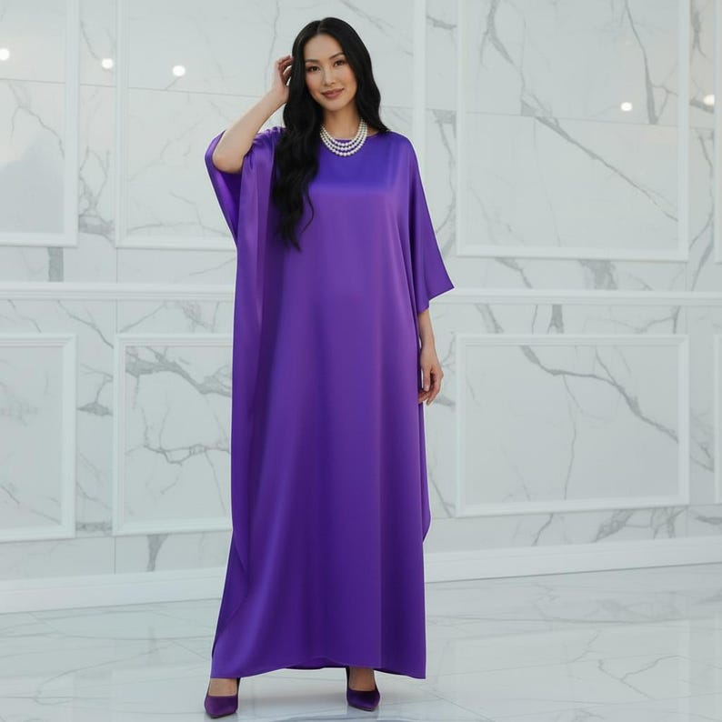May include: A long, flowing, purple satin dress with wide sleeves. The dress has a simple, elegant design and is worn with matching purple heels. A pearl necklace adds a touch of sophistication. The dress is suitable for formal occasions.