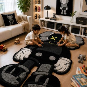 Puede incluir: Una alfombra grande de color negro y gris con forma de personaje de dibujos animados, con ojos en forma de X, manos con guantes blancos y pies redondeados. La alfombra presenta una superficie texturizada con contornos negros y detalles grises.