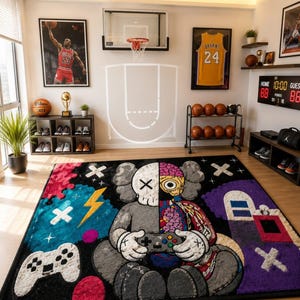 Puede incluir: Una alfombra rectangular que presenta un personaje con dise&ntilde;o dividido, con un lado gris y el otro mostrando detalles anat&oacute;micos. La alfombra incluye un mando de juego blanco, un rayo amarillo y detalles morados sobre un fondo negro.