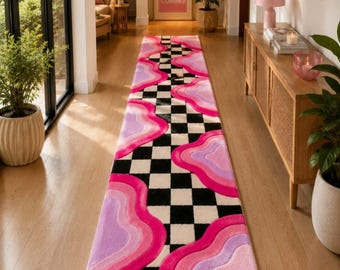 Könnte beinhalten: Ein langer, rechteckiger Läufer mit einem zentralen schwarz-weißen Schachbrettmuster, flankiert von asymmetrischen, wellenförmigen, geschichteten Formen in den Farben Pink, Hellrosa und Lavendel, die von den Rändern zur Mitte verlaufen.