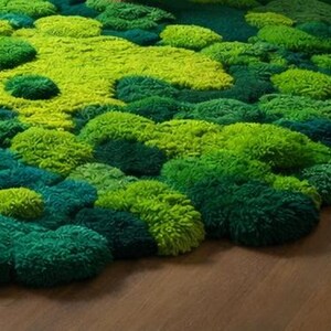 May include: A vibrant, textured rug in shades of green, resembling a mossy landscape. The rug features a variety of green hues, from deep emerald to bright lime, creating a natural, organic aesthetic. The rug's design is reminiscent of a forest floor.
