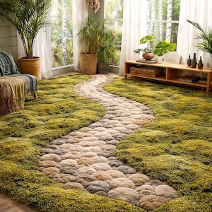 Könnte beinhalten: Ein grüner und beiger Teppich mit einem gewundenen Steinweg-Design. Der Teppich hat ein weiches, strukturiertes Aussehen, mit einem moosartigen grünen Hintergrund und einem Weg aus beigen und grauen Steinen. Der Teppich befindet sich in einem Raum mit Pflanzen und Tageslicht.