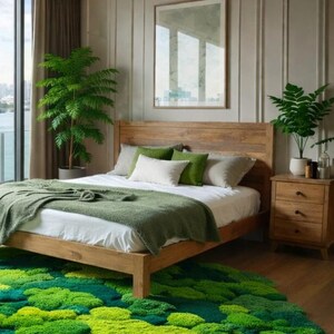 May include: A bedroom with a wooden bed frame, a green blanket, and pillows. A round, moss-like rug in shades of green sits on the floor. A wooden nightstand and a large window with a view complete the scene.