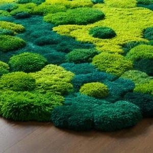 May include: A vibrant, textured rug featuring a layered design of green moss. The rug showcases a variety of shades, from deep forest green to bright lime, creating a natural, organic aesthetic. The rug is placed on a wooden floor.