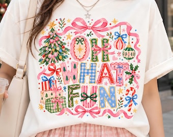 May include: A white t-shirt featuring a colorful Christmas-themed graphic with the text "OH WHAT FUN". The design includes a decorated tree, stacked gift boxes, candy canes, ornaments, and pink ribbons, all rendered in a festive, illustrated style.