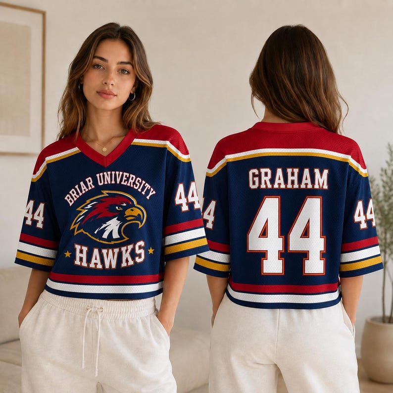 A woman wearing a blue and red sports jersey with the name 'Graham' and the number 44 on the back, standing in front of a white wall.