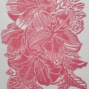 Op de afbeelding: Een rood-witte linosnede van een bloemencluster en bladeren. De print is getiteld "Spring Bloom" en gesigneerd "M. Vickers 2026". Het kunstwerk heeft gedetailleerde lijnen, wat een textuureffect creëert.