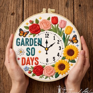 May include: A round embroidery hoop clock featuring the text GARDEN SO DAYS in teal and orange thread. The clock face is decorated with embroidered red, pink, and yellow flowers, green leaves, and two butterflies on a white fabric background.