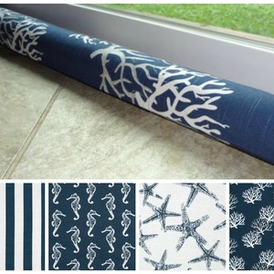 May include: A blue and white doorstop with a coral reef design. The doorstop is made of fabric and is filled with a soft material. The doorstop is shown on a tiled floor. The image also shows four different fabric patterns: stripes, seahorses, starfish, and coral.