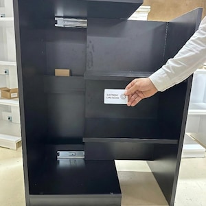 Puede incluir: Un mueble de madera negro con estantes y un cajón extraíble. El mueble tiene un diseño moderno e incluye el texto "ELECTRONIC CARD ACCESS".
