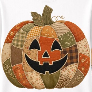 Puede incluir: Una camiseta blanca con un gráfico central grande de una calabaza de Halloween. La calabaza presenta un diseño de patchwork en varios tonos de naranja, marrón y verde, con texturas de tela que incluyen motivos florales, cuadros y colores lisos.