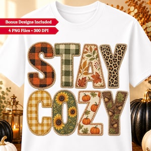 May include: A white t-shirt featuring the text STAY COZY in large letters. Each letter has a unique pattern: orange and black plaid, green plaid, autumn leaves, leopard print, yellow gingham, sunflowers, pumpkins, and acorns with oak leaves.