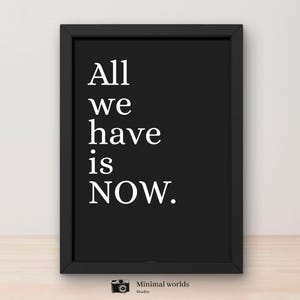 Op de afbeelding: Een zwart-wit afdruk met de tekst "All we have is NOW." Het minimalistische ontwerp heeft een zwarte lijst en witte tekst, geschikt voor huis- of kantoordecoratie. De rechterbenedenhoek heeft het logo van Minimal worlds studio.