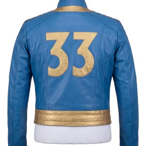 May include: A blue leather jacket featuring a gold collar and a gold waistband. The back of the jacket displays the large gold number 33 centered on the blue leather panel. The jacket has long sleeves and a structured fit, shown on a mannequin.