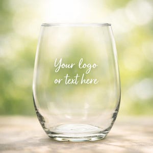 Op de afbeelding: Een helder, steelloos glas met de in wit gedrukte tekst "Your logo or text here" in het midden. Het glas heeft een afgeronde, gebogen vorm met een gladde rand en een dikke, massieve glazen bodem, geschikt voor het serveren van diverse dranken.