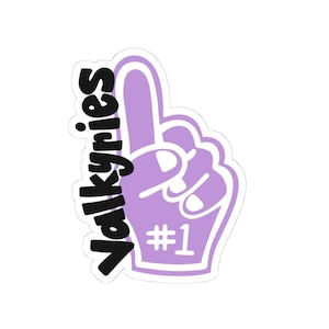 May include: A purple foam finger with the word "Valkyries" in black script on the side. The number "#1" is printed in white on the palm of the hand. The foam finger is a fan accessory.