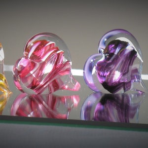 May include: Four glass heart ornaments in different colours: yellow and white, pink and white, purple and white, and blue and white.